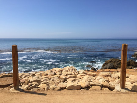 Seaside View With Calm Waters and Rocky Shore Under a Clear Blue Sky in a Tranquil Coastal Settingの写真素材