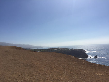 Coastal View of a Serene Shoreline and Distant Hills During a Sunny Afternoon Near the Oceanの写真素材