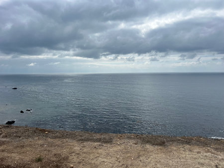 Vast Ocean Stretches Under a Cloudy Sky, Inviting Reflection and Calmness Near the Coastline at Duskの写真素材