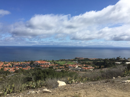 Scenic Coastal View Showcasing Vibrant Homes and Calm Ocean Under a Partly Cloudy Sky in the Afternoon Lightの写真素材