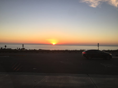 Sunset Paints the Sky With Vibrant Colors Over the Ocean Near a Calm Coastal Roadの写真素材