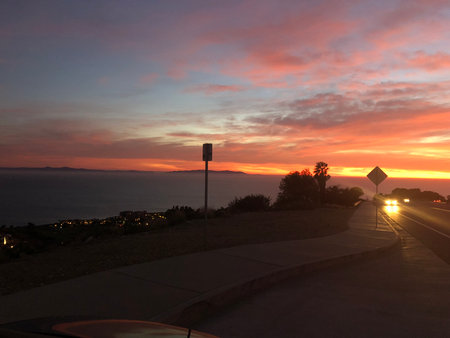 Stunning Sunset Over the Ocean Paints the Sky in Brilliant Hues Near Coastal Roadの写真素材