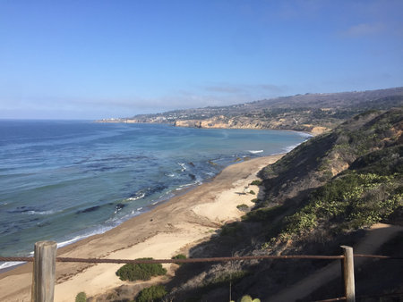 Scenic Coastal View of a Tranquil Beach and Cliffs Under a Bright Blue Sky During a Sunny Dayの写真素材
