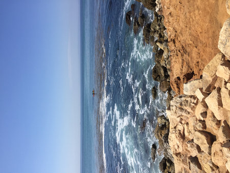 Kayakers Exploring the Tranquil Waters Along a Rocky Coastline on a Sunny Dayの写真素材