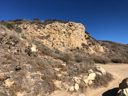 Natural Landscape Showcasing Rugged Cliffs and Dry Terrain Under a Clear Blue Sky on a Sunny Dayの写真素材