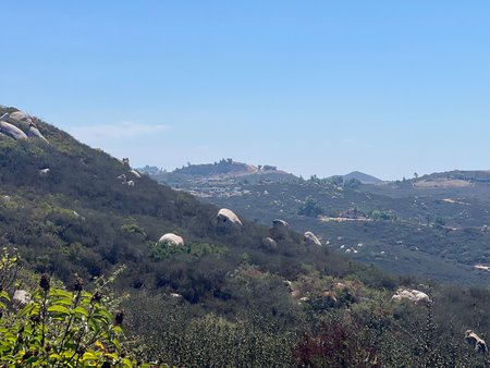 Scenic View of Rolling Hills and Boulders Under a Clear Blue Sky in a Serene Landscape During Middayの写真素材