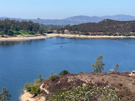 Tranquil Waters at the Lake Surrounded by Hills Under Clear Blue Skies in the Afternoon Sunlightの写真素材