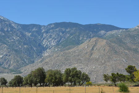 Majestic Mountains Rise Above the Serene Valley Under a Clear Blue Sky in This Peaceful Natural Landscapeの写真素材