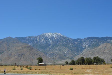 Majestic Snow-Capped Mountains Rise Above a Tranquil Landscape Under a Clear Blue Sky in the Sunny Afternoonの写真素材