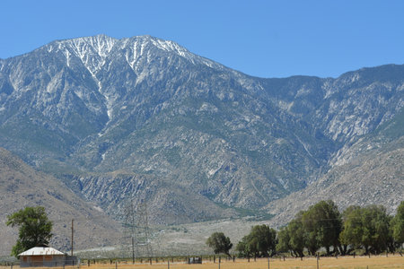 Majestic Mountains Tower Over a Serene Valley Scene With Clear Blue Skies and Hints of Snow Atop Peaksの写真素材