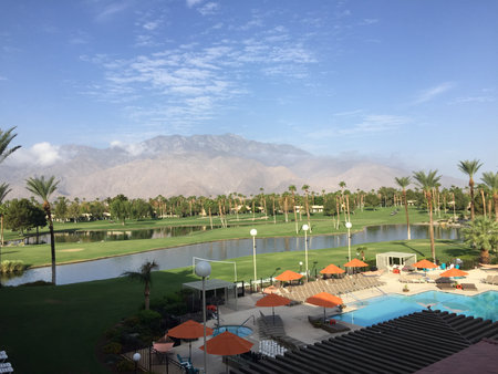 Stunning View of a Tranquil Resort With a Pool, Palm Trees and Mountains Under a Clear Sky in the Afternoonの写真素材