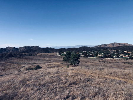 Expansive View of Rolling Hills and Distant Homes Under a Clear Blue Skyの写真素材