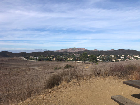 Scenic View of Rolling Hills and a Quiet Town Nestled in the Valley Beneath a Clear Blue Skyの写真素材