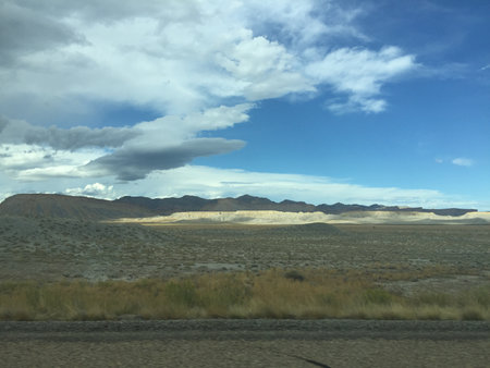 Mountains Rise Under a Sweeping Sky Filled With Clouds and Warmth Across the Vast Desert Landscape in the Afternoon Lightの写真素材