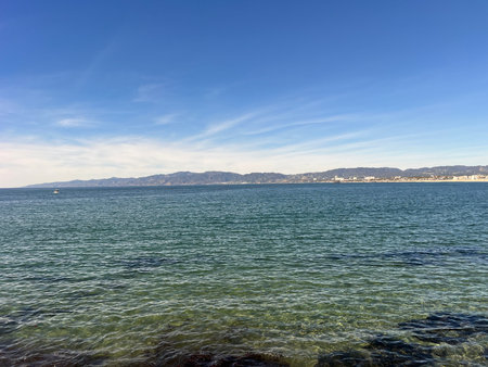 Endless Blue Ocean Stretches Under a Clear Sky With Gentle Waves Lapping at the Shoreの写真素材