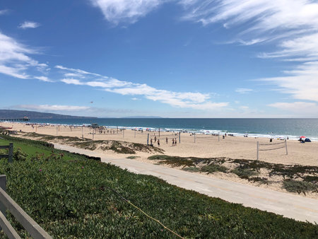 Relaxing Beach Day With People Enjoying Volleyball and Sunshine on a Sunny Coastの写真素材