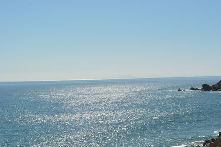 Shimmering Ocean Water Under a Bright Blue Sky, Capturing the Serene Beauty of Coastal Tranquility in Midday Lightの写真素材