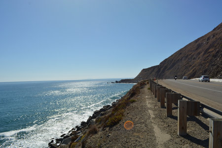 Scenic Coastal View With Glistening Water and Rugged Cliffs Along the Highwayの写真素材