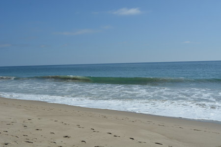 Gentle Waves Lap Against a Sandy Shore on a Bright Sunny Day by the Ocean's Edgeの写真素材