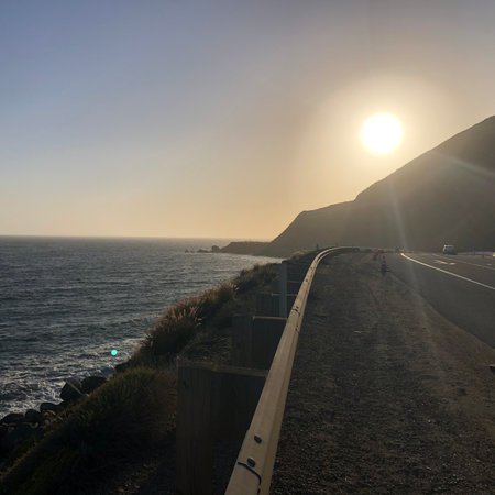 Sunset Over the Coastal Highway With Ocean Waves and Rocky Cliffs in the Background During Golden Hourの写真素材