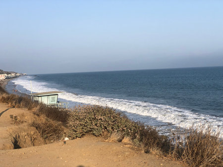 Waves Crashing Gently Against the Sandy Shore at a Tranquil Beach in the Late Afternoon Sunの写真素材