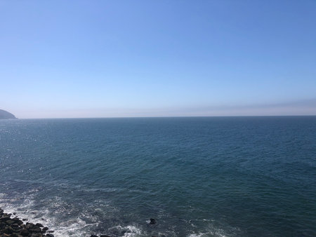 Tranquil Ocean View From Rocky Coast Under a Clear Blue Sky, Inviting Relaxation and Reflection at Middayの写真素材
