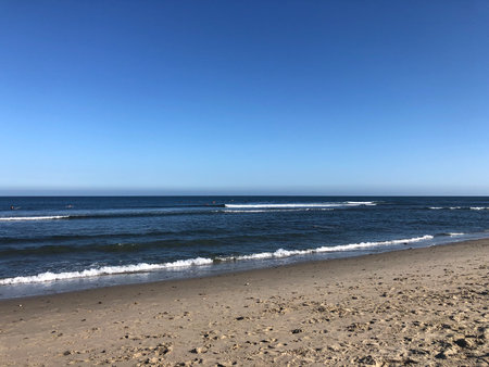 Sunny Beach Scene Showcasing Gentle Waves and Clear Blue Sky Near the Coast in Mid-Morning Lightの写真素材