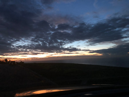 Sunset Over the Ocean With Dramatic Clouds and Twilight Colors From a Scenic Driveの写真素材