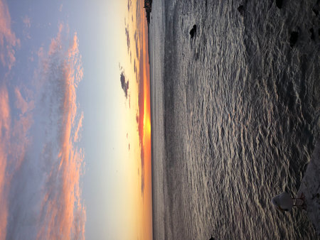 Vibrant Sunset Paints the Ocean Sky in Stunning Hues Over Calm Waters in a Coastal Paradiseの写真素材