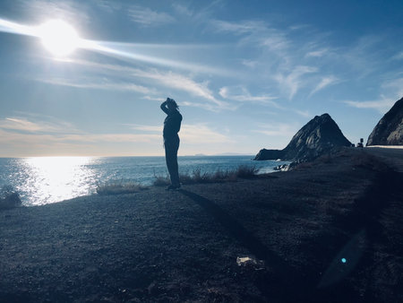 Silhouette Against the Sparkling Sea at Sunset on a Coastal Path With Rugged Cliffsの写真素材