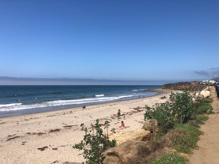 Waves Crash on the Sandy Shore as Families Enjoy a Sunny Day at the Beach in Southern Californiaの写真素材