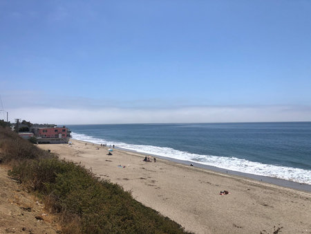 Gentle Waves Lap Against the Shore Under a Clear Blue Sky at a Peaceful Beach Locationの写真素材