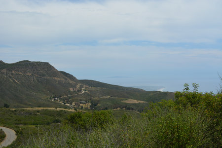 Scenic View of Winding Road Through Rolling Hills and Distant Ocean in Bright Daylightの写真素材