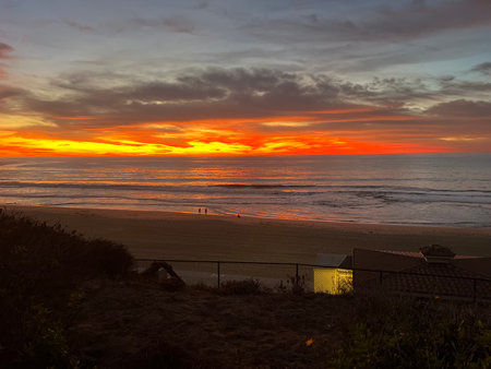 Sunset Colors Dance Across Ocean Waves at a Serene Beach, Creating a Picturesque Moment for Onlookersの写真素材