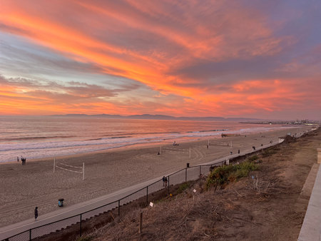 Colorful Sunset Illuminates Beach Scene With Vibrant Clouds and Serene Wavesの写真素材