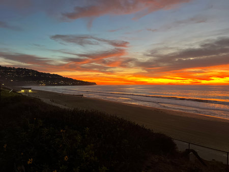 Stunning Sunset Over the Serene Beach as Waves Gently Lap the Shore in a Picturesque Coastal Settingの写真素材