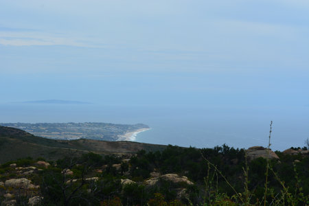 Serene Coastal View From the Hillside Overlooking the Calm Ocean and Distant Islands During a Peaceful Middayの写真素材