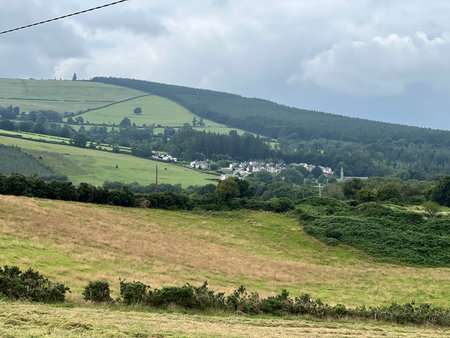 Scenic View of Rolling Hills and Tranquil Village in the Countryside During an Overcast Dayの写真素材