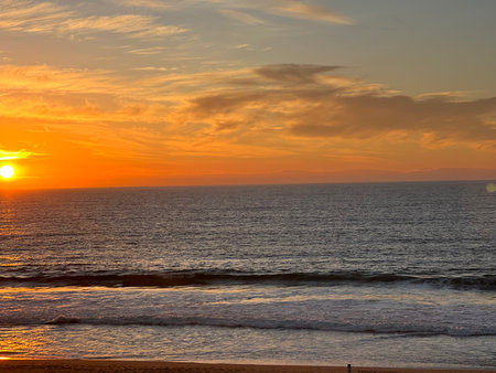 Sunset Paints the Ocean Sky in Vibrant Hues Over Tranquil Waves Near the Shoreの写真素材