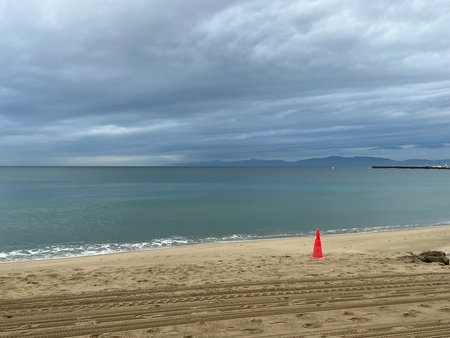 Serene Beach Viewed Under Cloudy Skies With Gentle Waves Lapping the Shore at Duskの写真素材
