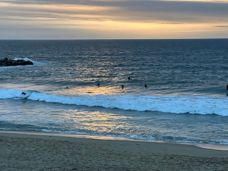 Surfers Ride the Waves at Sunset on a Calm Beachの写真素材