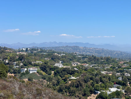 Scenic View of Rolling Hills and Modern Homes Under a Bright Blue Sky Near a Mountain Rangeの写真素材