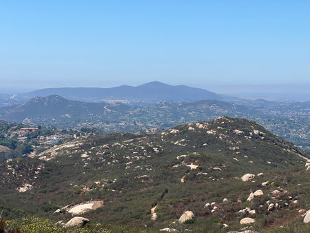Scenic View of Rolling Hills and Distant Mountains Under a Clear Blue Sky During Middayの写真素材
