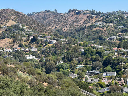 Scenic View of Lush Hills and Hillside Homes in a Vibrant Neighborhood During a Sunny Dayの写真素材