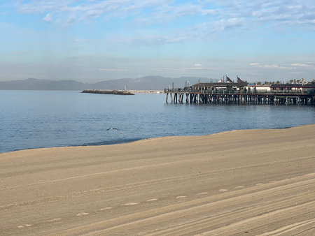 Calm Beach Scene Captures a Serene Morning With Gentle Waves and a Distant Pier Against a Clear Skyの写真素材