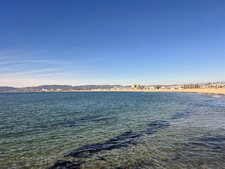 Seaside View on a Clear Day Showcases Calm Waters and Distant City Skyline Under Blue Skiesの写真素材