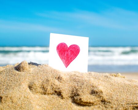 Heart drawn on a little piece of paper at the beachの写真素材