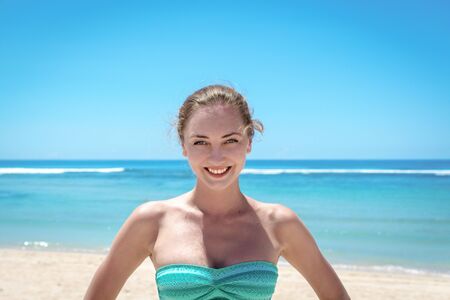 Young attractive woman posing and smiling at camera in front of sea shoreの写真素材