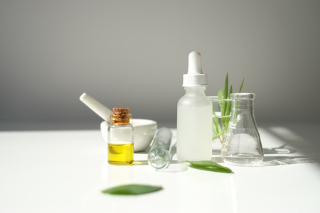 blank cosmetic  white serum dropper bottle containers with herbal ingredient and laboratory glass ware. package for branding .Natural organic beauty skincare product concept. alternative medicine.の写真素材