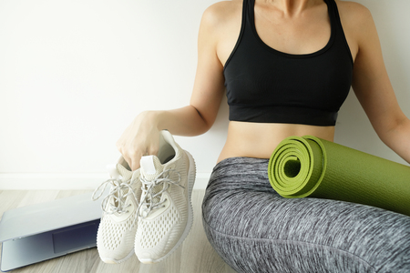 woman stop to work and workout or fitness at home for balance idea. close computer hold yoga mat. balancing life concept.の写真素材